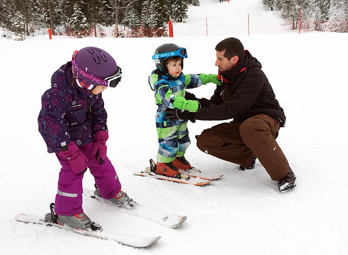 papa qui apprend le ski à sa fille et son garçon