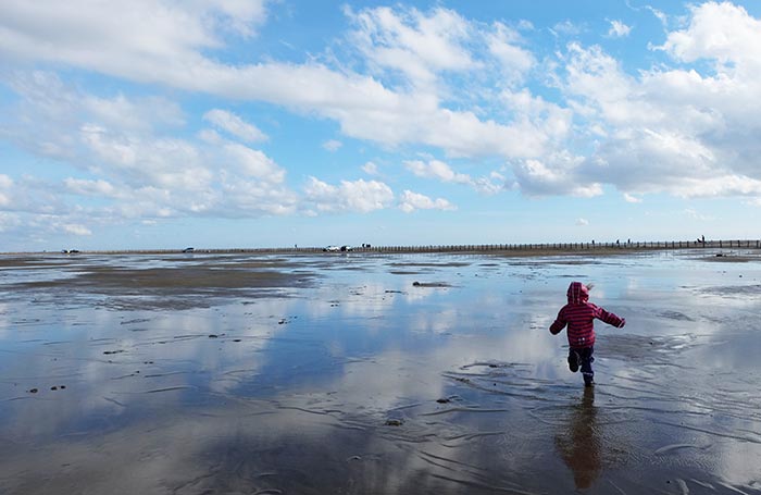 Erin court en bottes sur le sable mouillé en Camargue au bord de mer