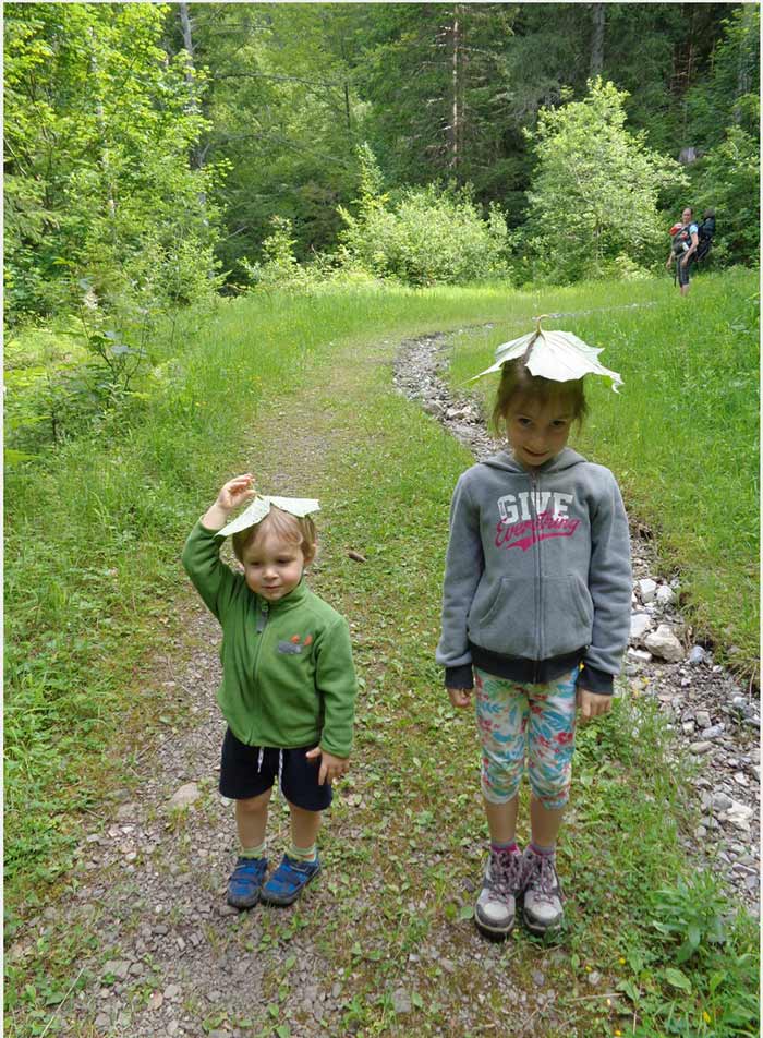 les enfants se fabriquent des chapeaux en feuilles trouvées lors de la rando