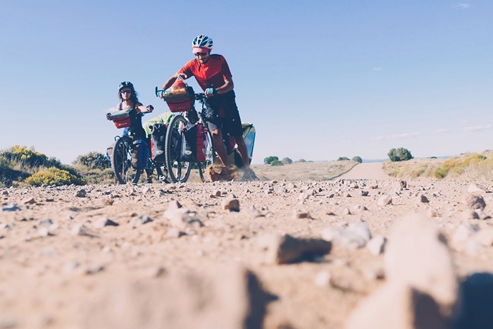 olivier et adeline poussent leur vélo sur la piste caillouteuse