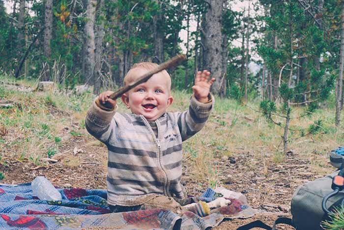 bébé joue avec un bâton au bivouac en forêt