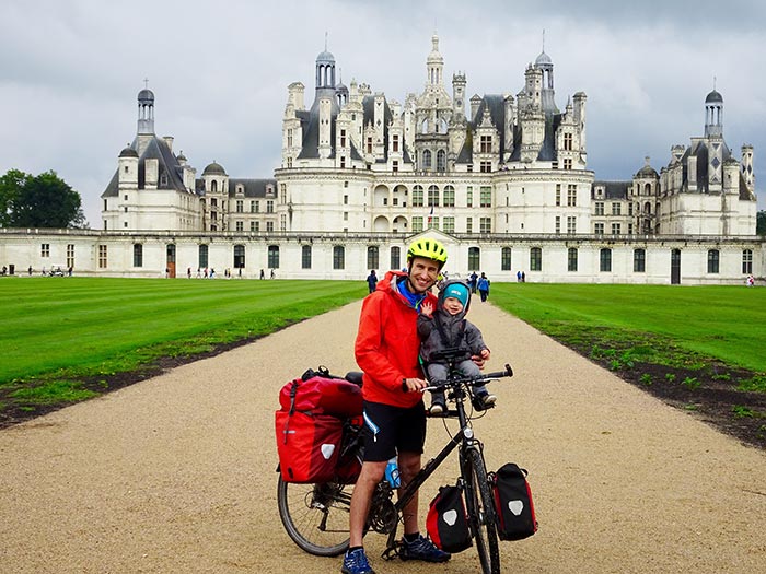 papa et enfant en vélo devant le château de Chambord