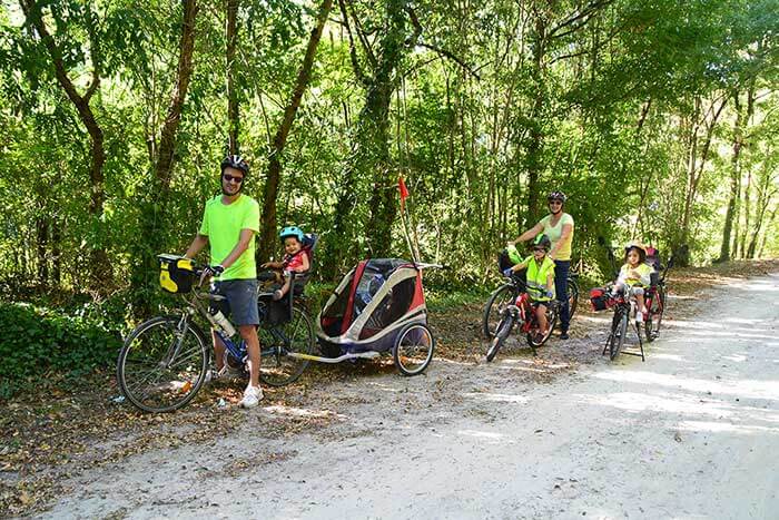 photo d'une famille sur la voie verte Passa Païs, avec remorque et siège vélo