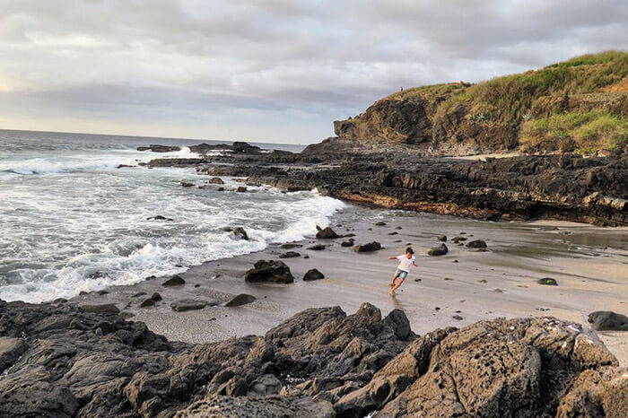 enfant qui joue sur une plage de sable noir sur l'île de la Réunion