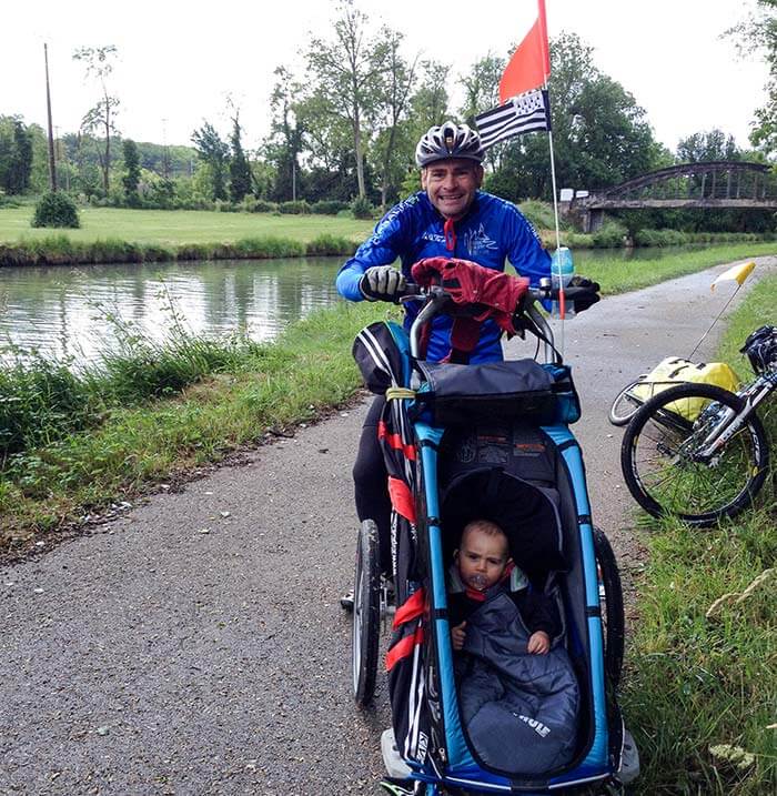 papa et son enfant dans une remorque vélo en mode poussette