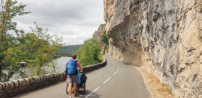 adulte en marche à pied pousse une carriole sur la route dans le Lot