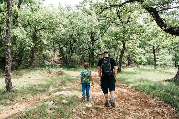 enfant et son papa en randonnée en forêt sur un chemin de terre à Montauroux