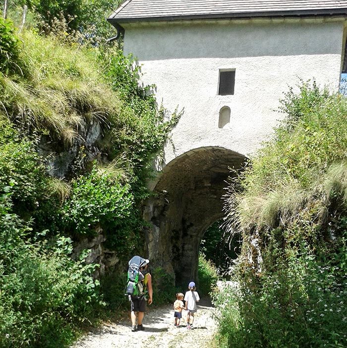 famille en balade passe sous une porte fortifiée