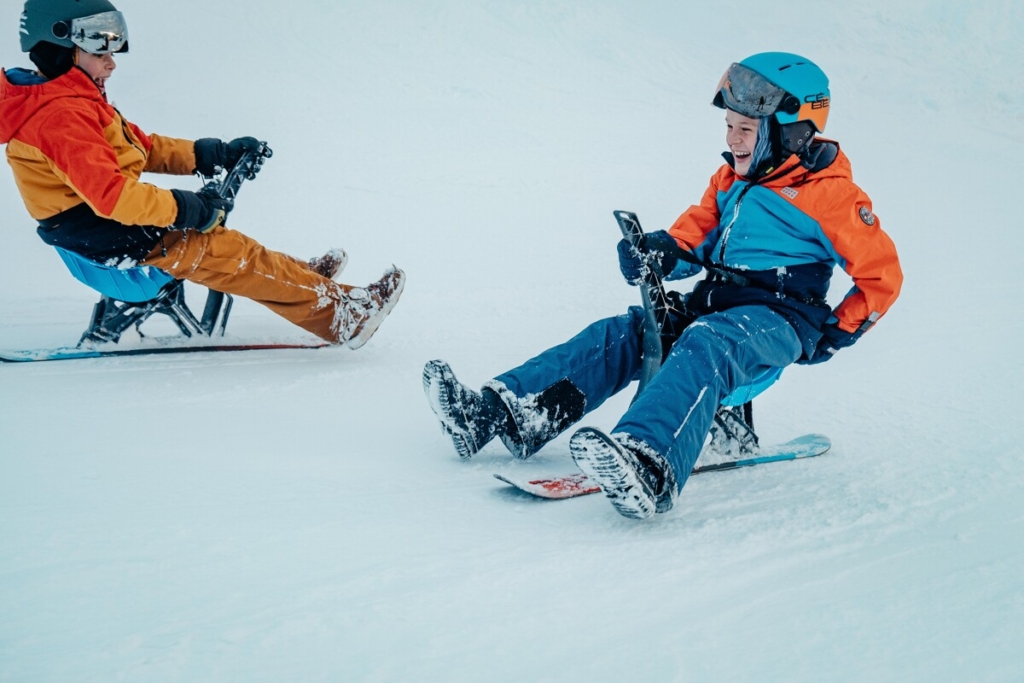 3 activités en famille en montagne l’hiver en Savoie Mont Blanc. des enfants descendent une piste en yooner