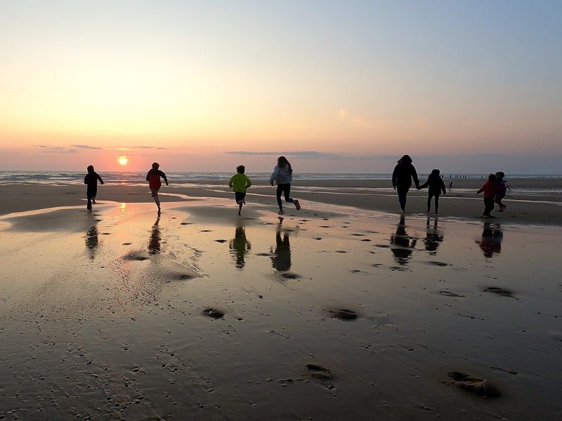des enfants courent vers l'océan au coucher du soleil