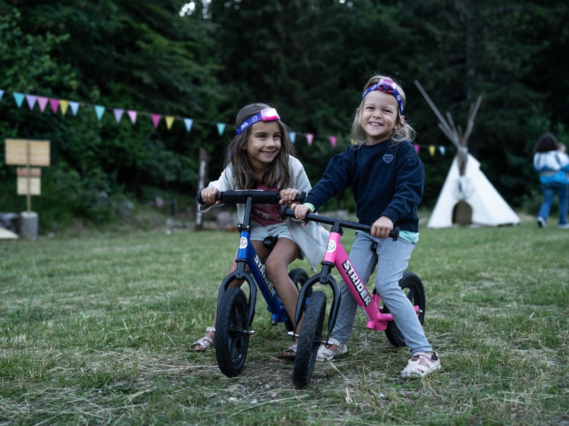 deux petites filles font de la draisienne au camp de base